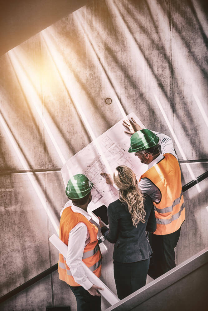 businesswoman-architects-standing-staircase-discussing-with-blueprint